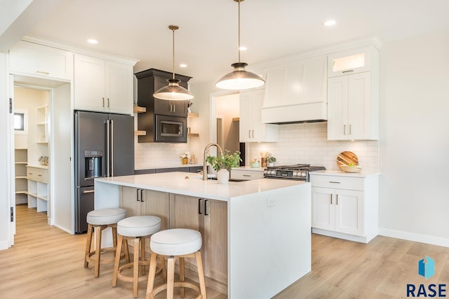 kitchen with white cabinetry, sink, pendant lighting, and a center island with sink