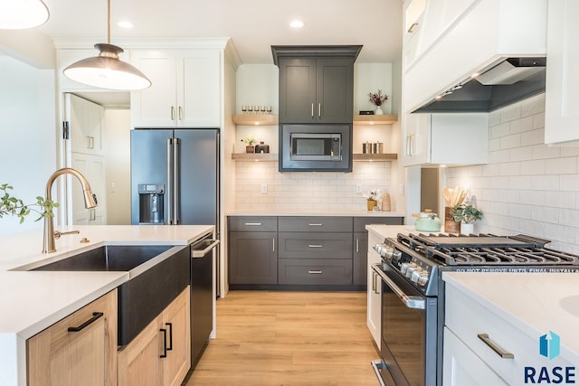 kitchen featuring custom exhaust hood, stainless steel appliances, gray cabinets, white cabinetry, and hanging light fixtures