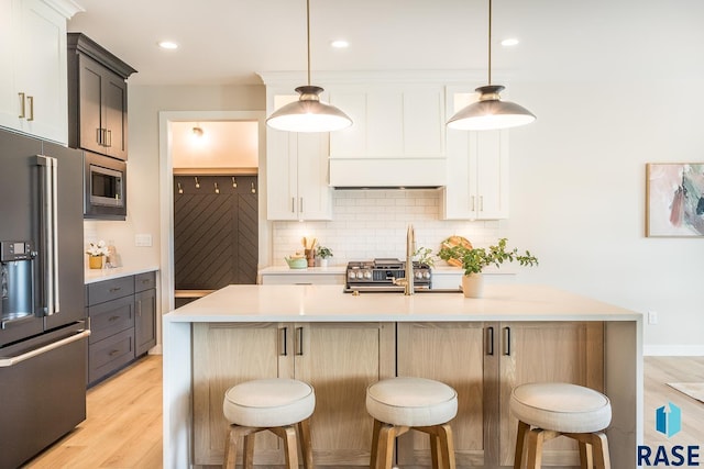 kitchen with white cabinetry, stainless steel appliances, and an island with sink