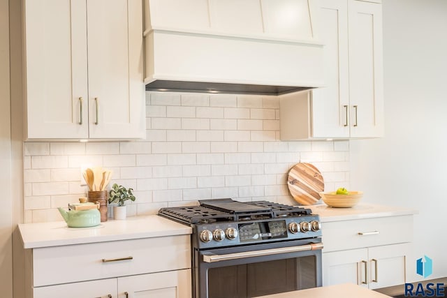 kitchen featuring decorative backsplash, white cabinetry, and high end stainless steel range oven