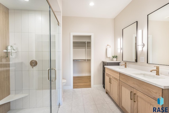 bathroom featuring tile patterned flooring, vanity, toilet, and a shower with door