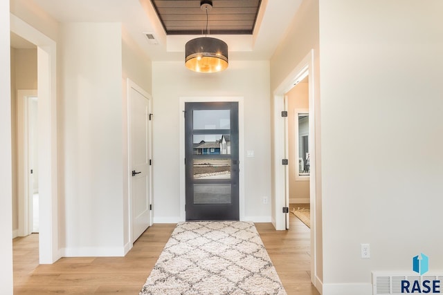 foyer entrance with light hardwood / wood-style flooring and a raised ceiling