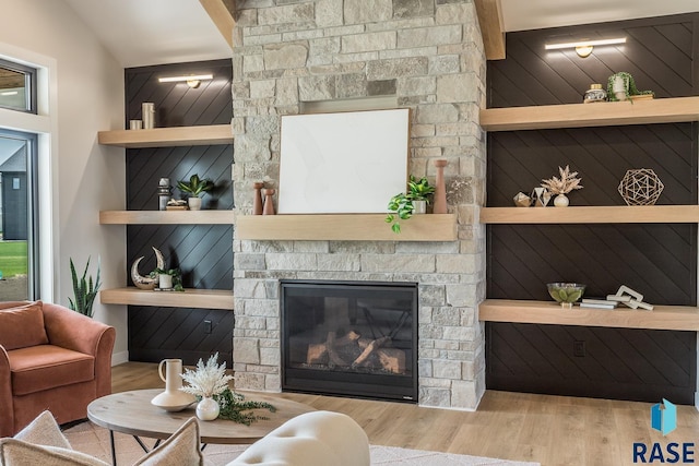 living room with built in shelves, a fireplace, and light hardwood / wood-style flooring