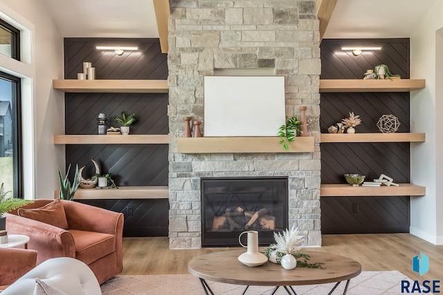 living room with a fireplace, built in shelves, and light wood-type flooring