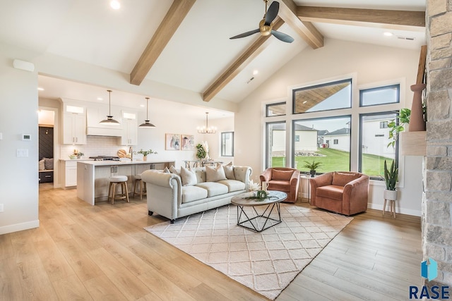 living room featuring beamed ceiling, ceiling fan with notable chandelier, and light hardwood / wood-style flooring