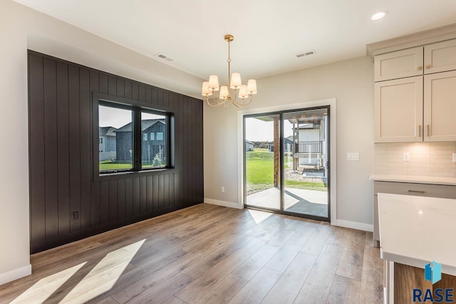 unfurnished dining area with light hardwood / wood-style floors and a notable chandelier