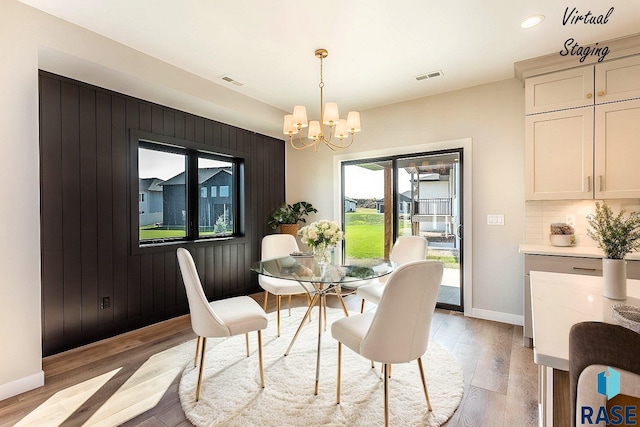 dining area with light hardwood / wood-style floors and a chandelier