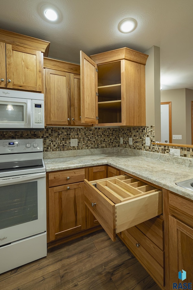 kitchen featuring light stone countertops, decorative backsplash, dark hardwood / wood-style flooring, and white appliances