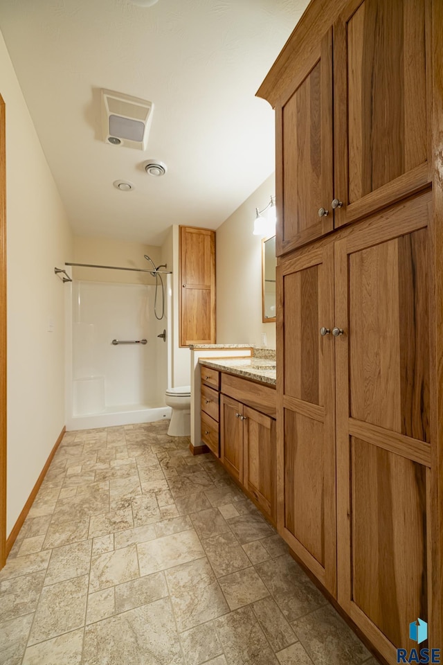 bathroom featuring a shower, vanity, and toilet