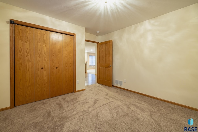 unfurnished bedroom with light carpet and a closet