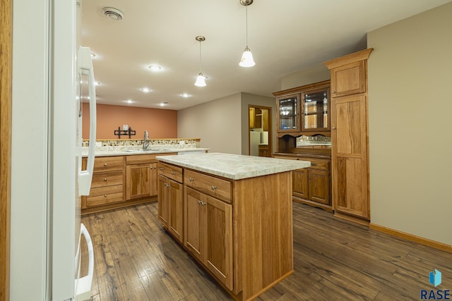 kitchen with a center island, sink, dark wood-type flooring, kitchen peninsula, and pendant lighting