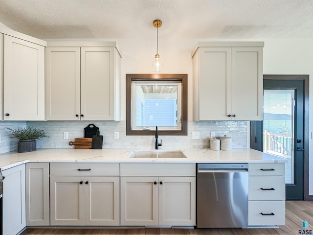 kitchen featuring light wood finished floors, decorative backsplash, dishwasher, pendant lighting, and a sink