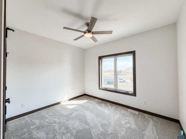 carpeted spare room featuring baseboards, visible vents, and a ceiling fan