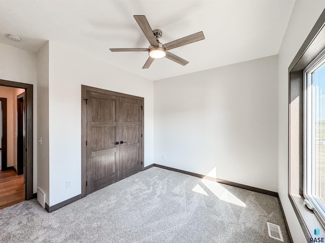 unfurnished bedroom with carpet floors, a closet, visible vents, and baseboards