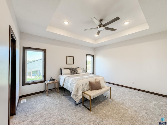 bedroom featuring light carpet, baseboards, and a tray ceiling