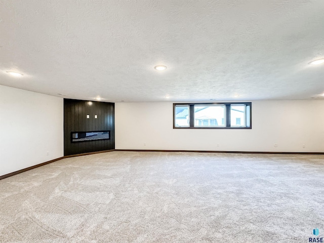 unfurnished living room with carpet floors, a textured ceiling, and baseboards