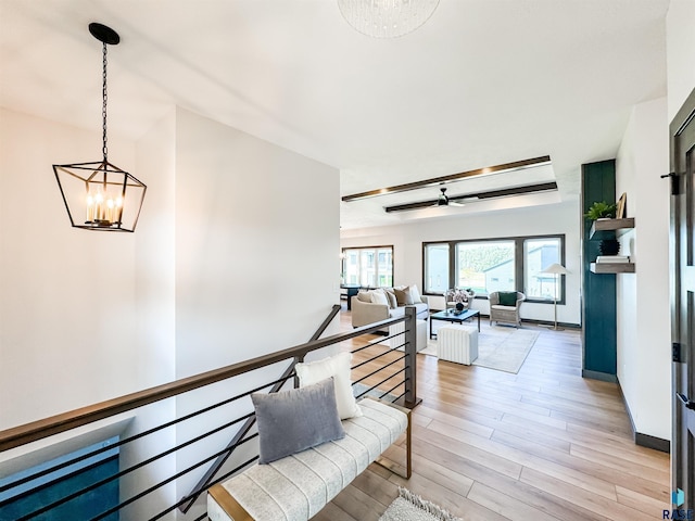 hallway with baseboards, light wood finished floors, an upstairs landing, and an inviting chandelier