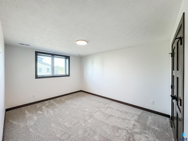 carpeted spare room featuring a textured ceiling, visible vents, and baseboards