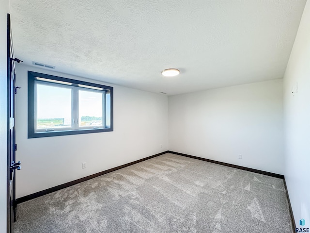 carpeted empty room with a textured ceiling, visible vents, and baseboards