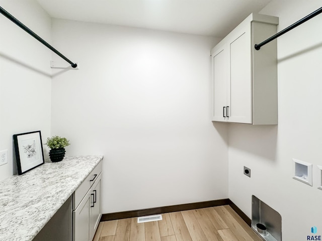 clothes washing area with visible vents, cabinet space, light wood-style flooring, electric dryer hookup, and baseboards