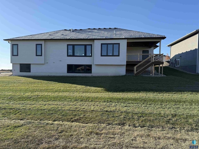 rear view of house featuring stairs, a deck, and a lawn