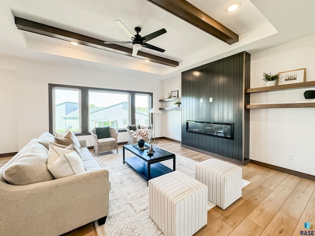 living room featuring light wood-style floors, beamed ceiling, baseboards, and ceiling fan