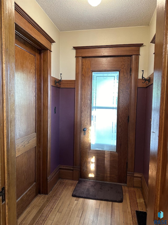 entryway featuring light wood-type flooring and a textured ceiling