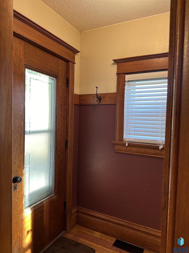 doorway with a healthy amount of sunlight, a textured ceiling, and hardwood / wood-style flooring