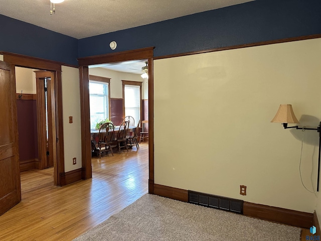 unfurnished room featuring ceiling fan, light hardwood / wood-style floors, and a textured ceiling