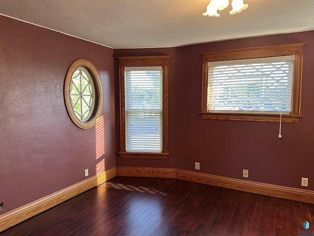 unfurnished room with a chandelier, a textured ceiling, and dark hardwood / wood-style flooring