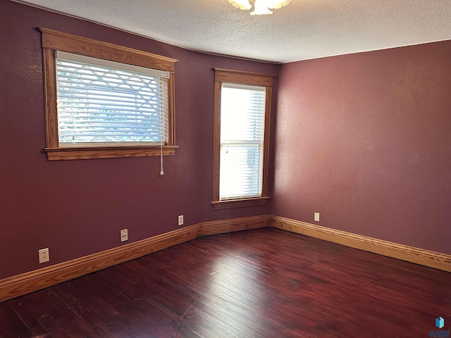 spare room featuring dark hardwood / wood-style flooring and a textured ceiling