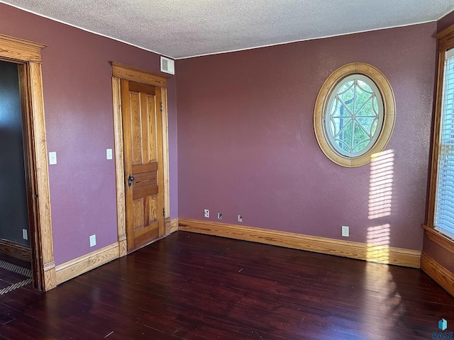 empty room featuring a textured ceiling and dark wood-type flooring