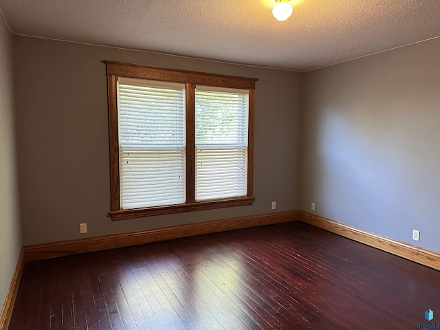 unfurnished room featuring dark wood-type flooring and a textured ceiling