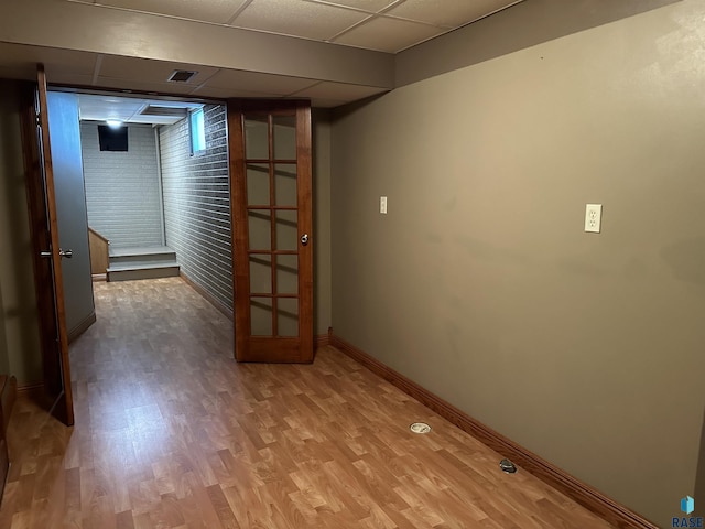 basement featuring a drop ceiling and hardwood / wood-style flooring