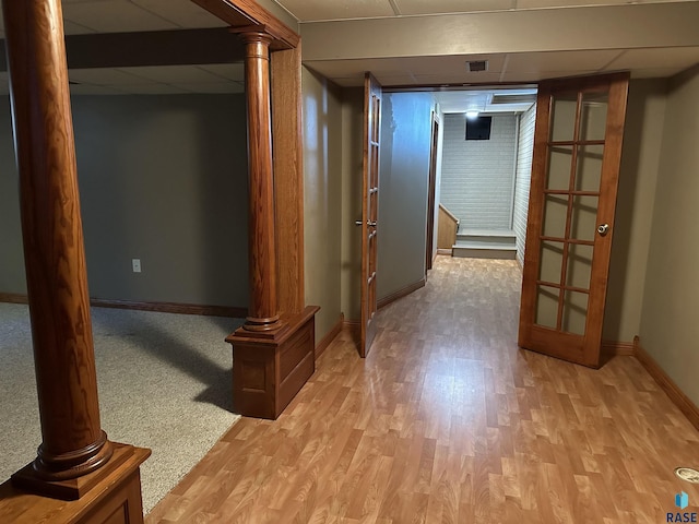 hall featuring a drop ceiling, light hardwood / wood-style floors, and ornate columns