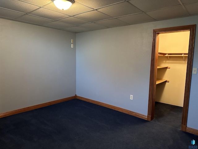 empty room with a drop ceiling and dark carpet