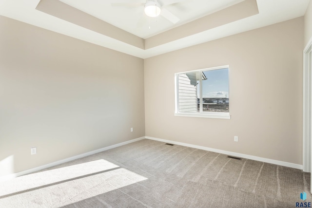 carpeted empty room featuring a raised ceiling and ceiling fan