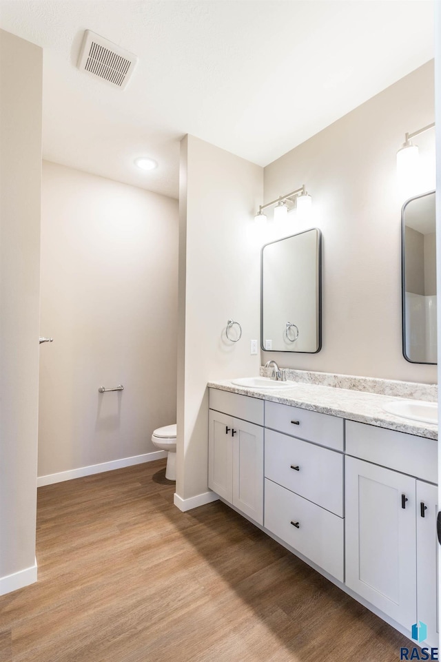 bathroom with toilet, vanity, and hardwood / wood-style flooring