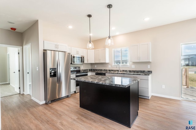 kitchen with dark stone counters, white cabinets, sink, a kitchen island, and stainless steel appliances