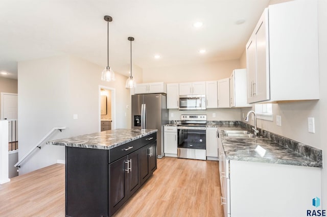 kitchen featuring a center island, sink, appliances with stainless steel finishes, decorative light fixtures, and white cabinetry