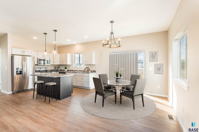 dining area featuring sink, a notable chandelier, and light hardwood / wood-style flooring