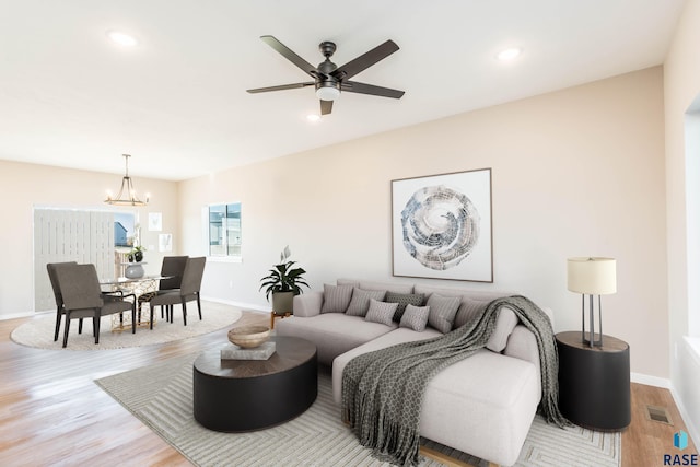 living room featuring light hardwood / wood-style floors and ceiling fan with notable chandelier