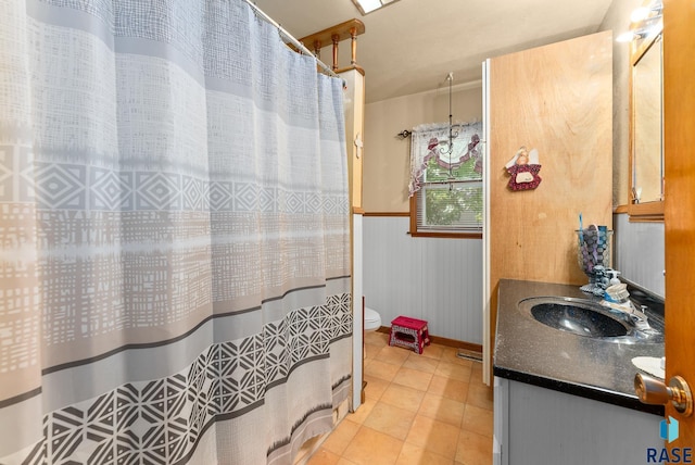 bathroom featuring tile patterned floors, vanity, toilet, and wood walls