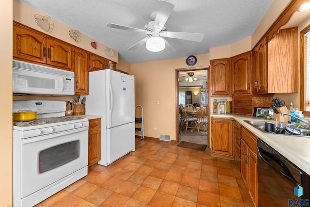 kitchen featuring a textured ceiling, ceiling fan, white appliances, and sink