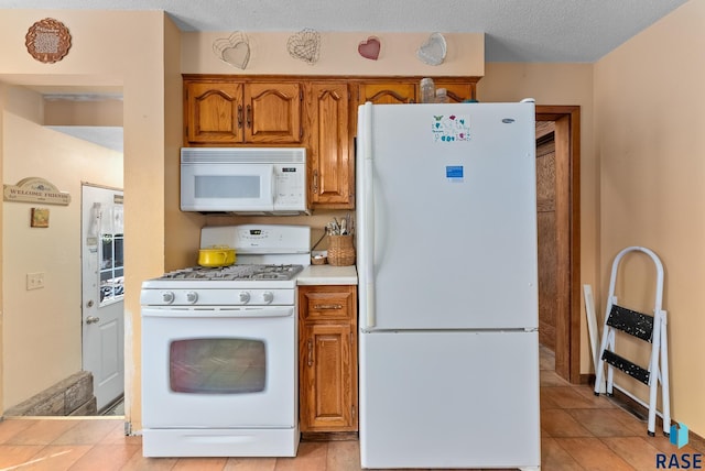 kitchen featuring white appliances, a textured ceiling, and light tile patterned floors