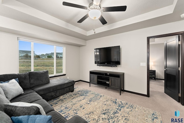 living room featuring light carpet, a raised ceiling, and ceiling fan