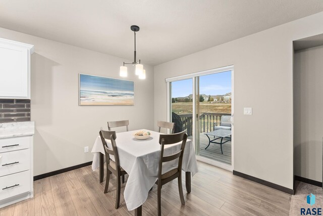 dining space with a notable chandelier and light hardwood / wood-style flooring