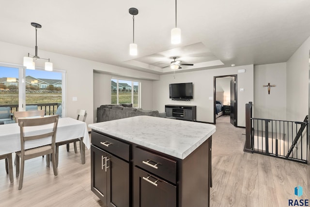 kitchen with a raised ceiling, ceiling fan, decorative light fixtures, and light wood-type flooring