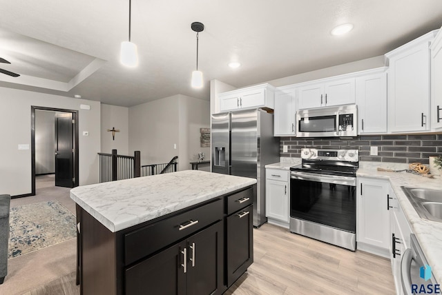 kitchen with a center island, white cabinets, hanging light fixtures, and appliances with stainless steel finishes