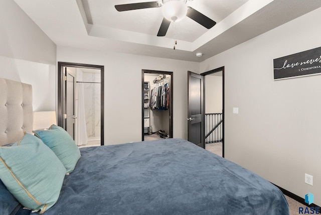 bedroom featuring ensuite bath, ceiling fan, a spacious closet, a tray ceiling, and carpet floors